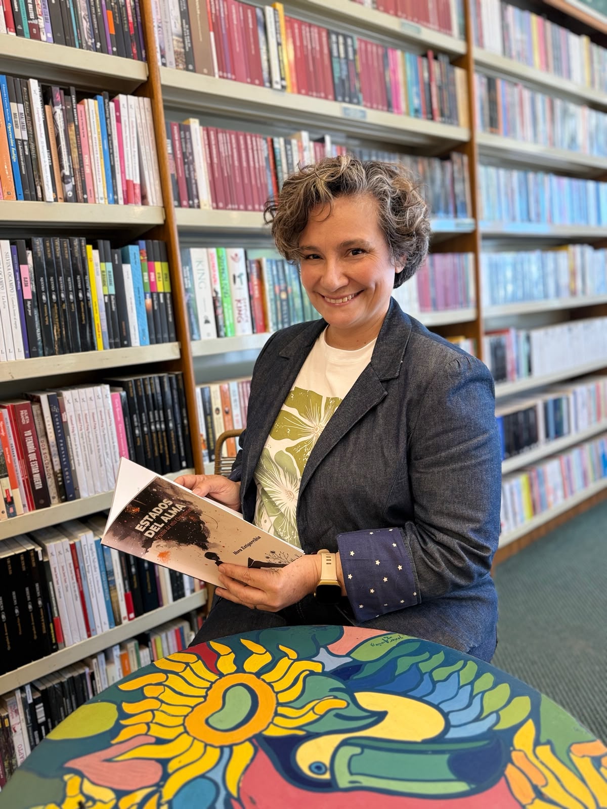 Nora Estigarribia sostiene su libro Estados del alma en una biblioteca